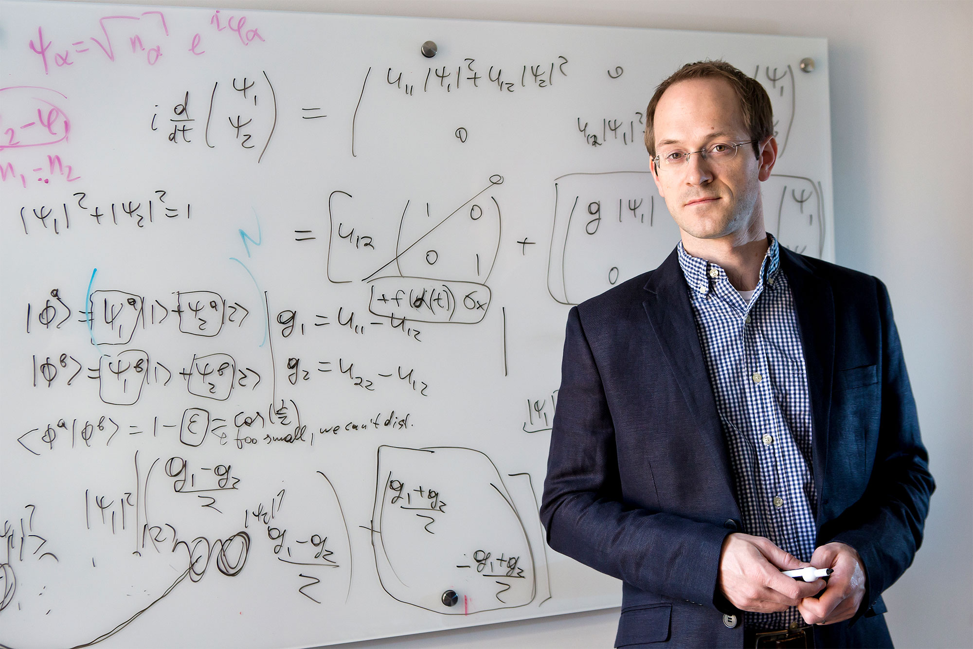 Photo of Andrew Childs standing in front of a white board full of math