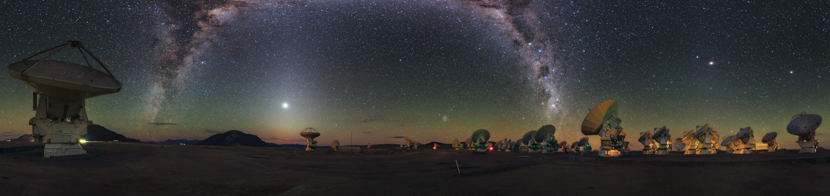 The ALMA Observatory’s antennas appear to take in the sight of the Milky Way, arching like a galactic rainbow of dust and stars over the Chajnantor Plateau in the Chilean Andes