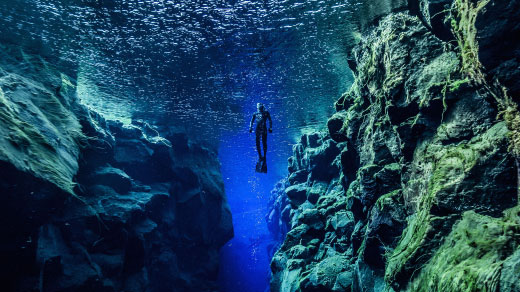 Photo of a diver between two tectonic plates in Silfra. reykjavik. Iceland