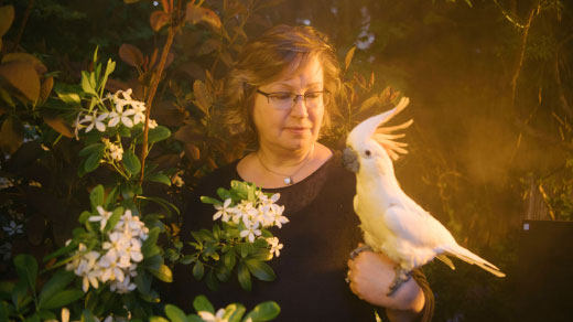 Victoria Meadows in her garden with her cockatoo.