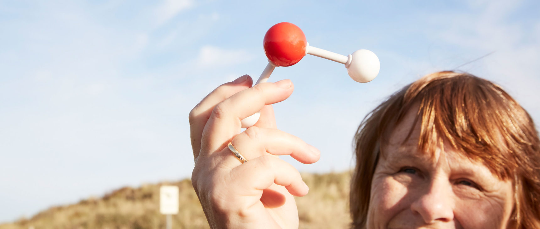 Ewine van Dishoeck at Noordwijk beach in the Netherlands, holding up a water molecule model.