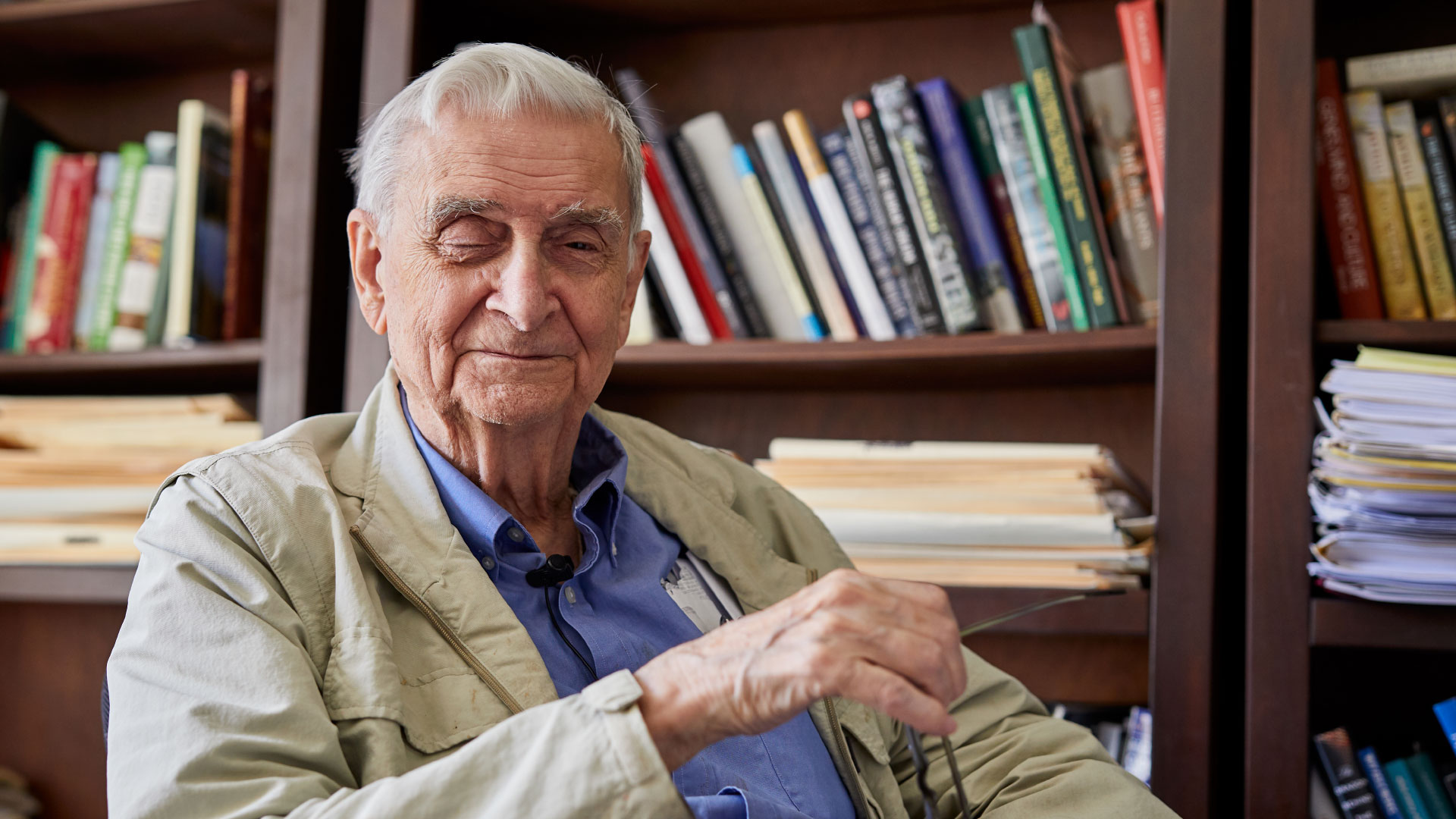 PHOTO: EO Wilson looking into the camera lens with eyeglasses in his hand.