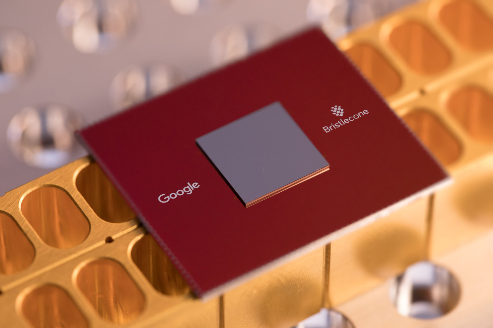 Photo of a quantum computer chip, a red metal plate with a smaller silver plate mounted on top.