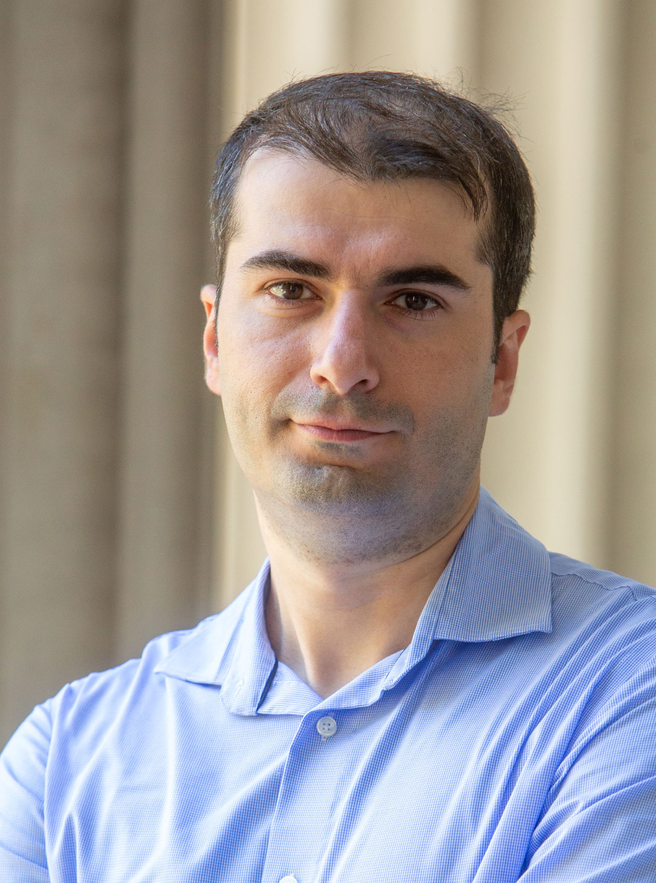 Photo of a man wearing a light blue collared shirt looking into the camera.