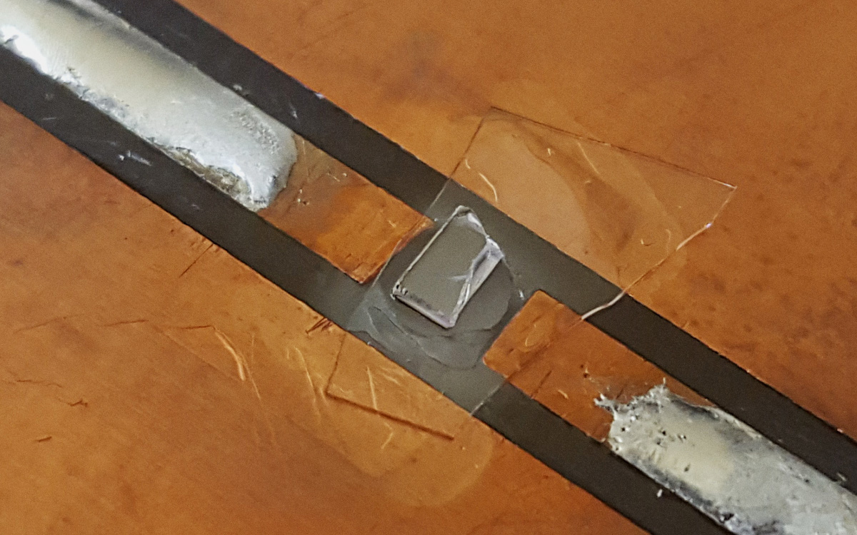 A photo of a flat, rough edged clear material on a slide.