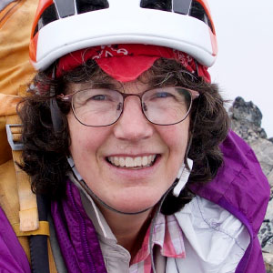 Nelson, wearing hiking gear, smiles at the camera at the top of a rocky outcrop.