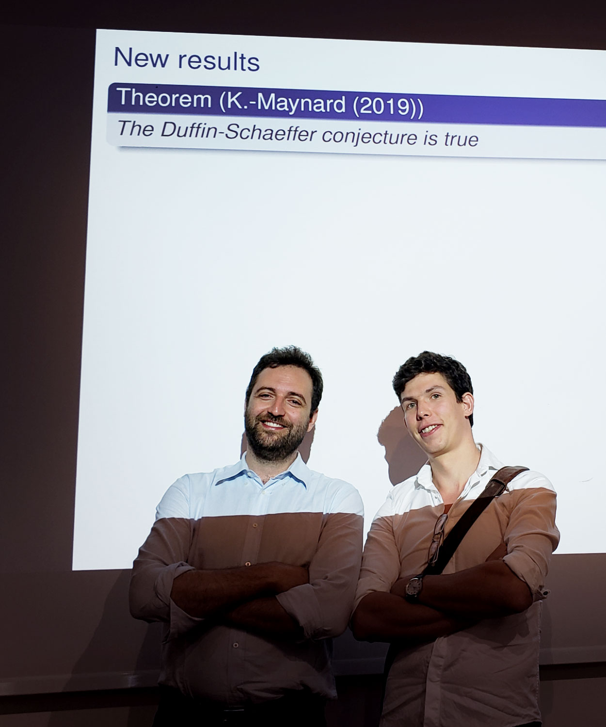 Two men in front of a projector screen.