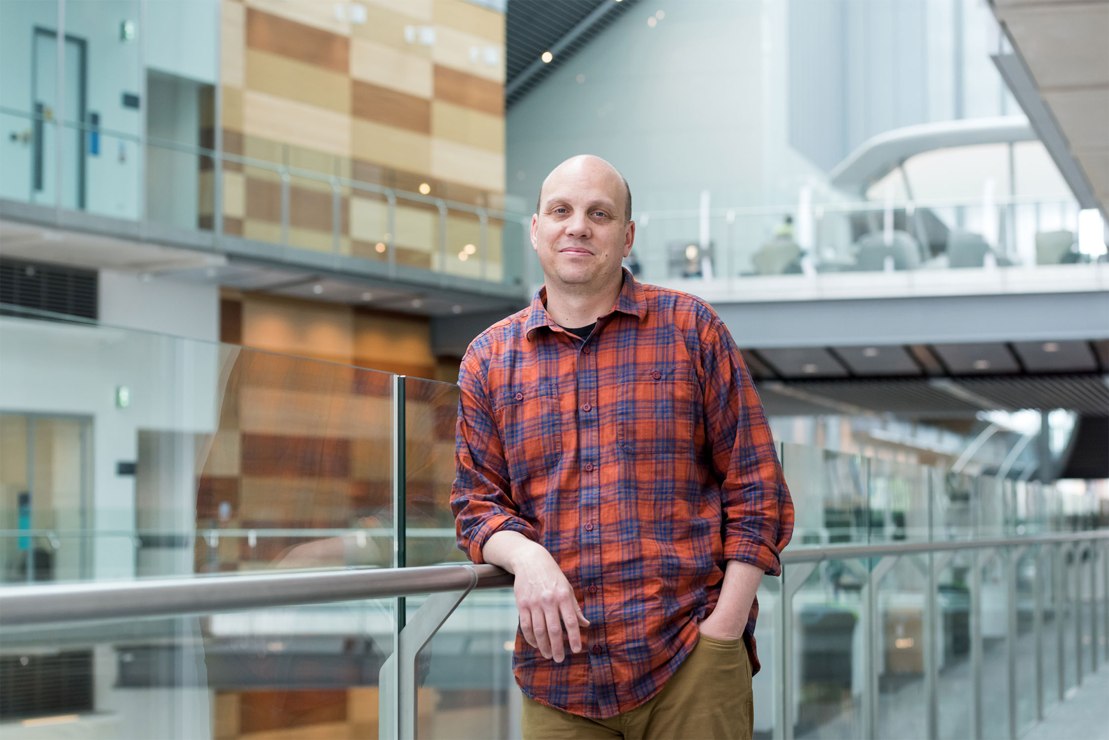 Nate Goehring leans against an elevated walkway railing inside the Francis Crick Institute.