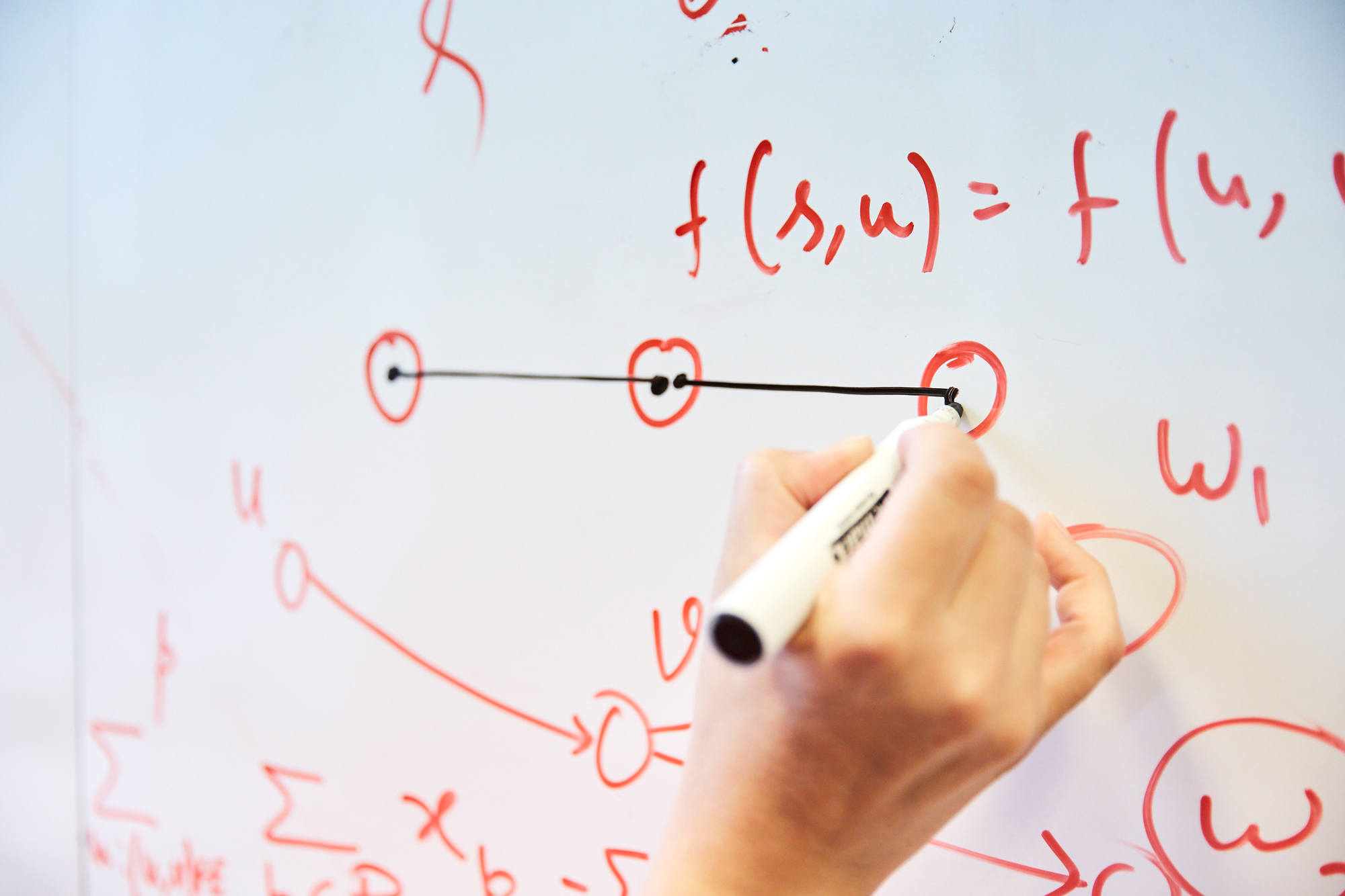 Close-up of Stephanie Wehner’s hand using a marker to draw three circles connected by lines on a dry-erase board.