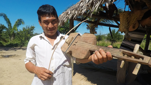 A Tsimané man plays an instrument resembling a violin.