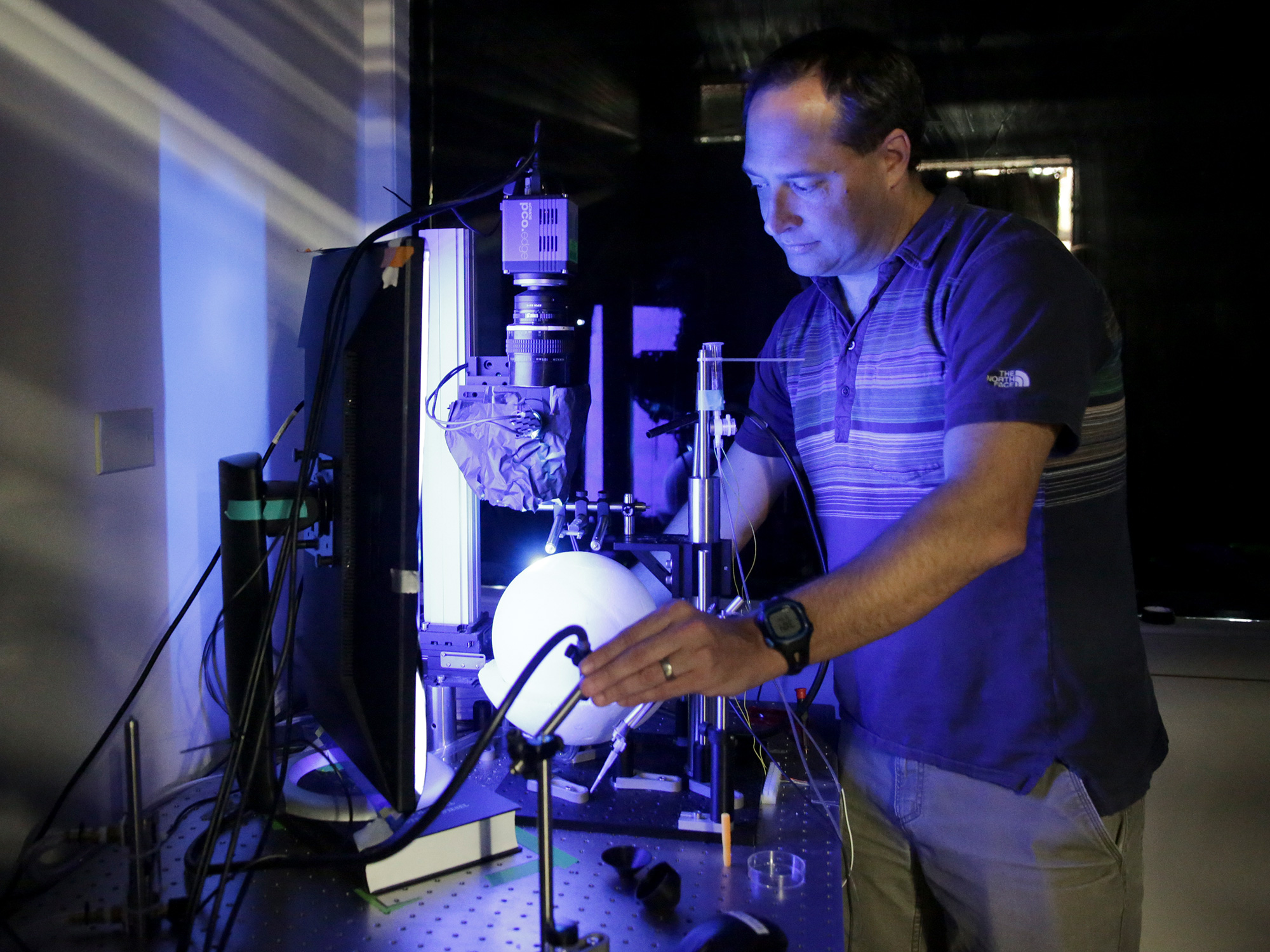 Neuroscientist Cris Niell in his laboratory, setting up his spherical treadmill testing device.