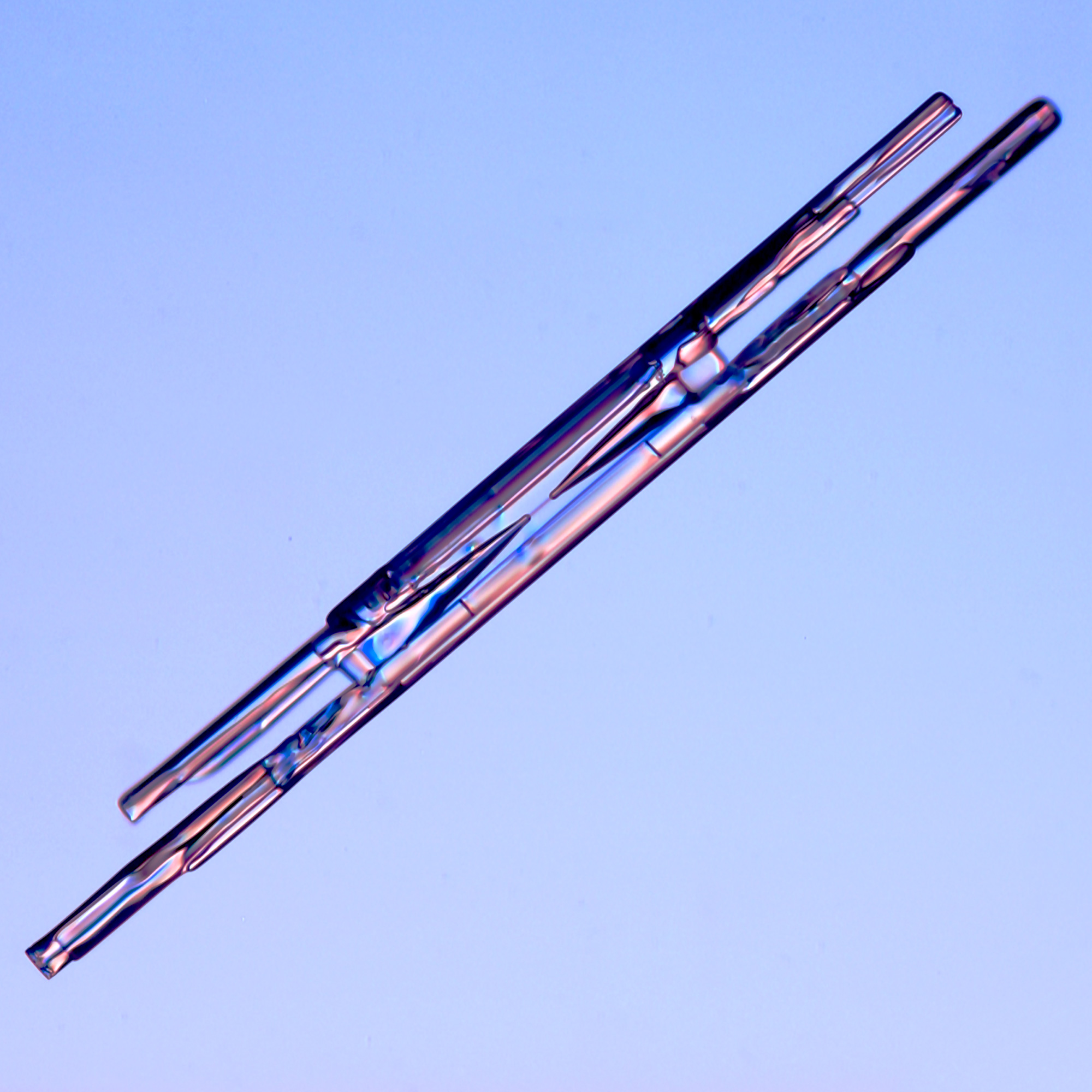 One of three close-up images of column-like snowflakes on a blue background.