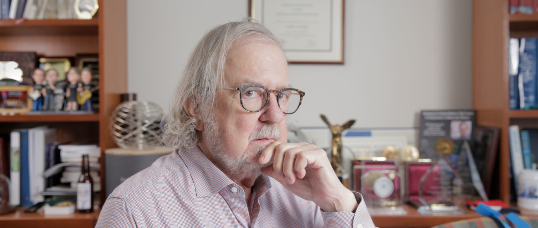 Photo of James P. Allison sitting at his desk at the MD Anderson Cancer Center.