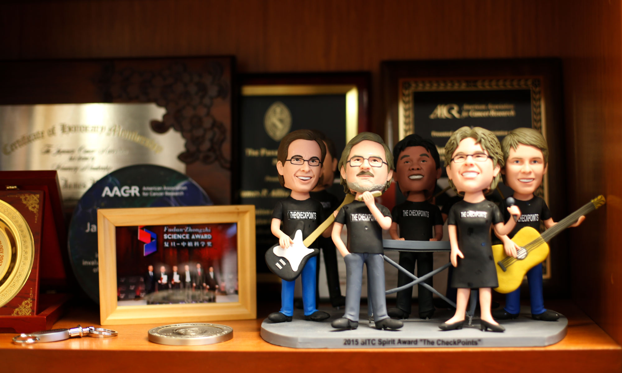 A bobblehead of Jim Allison and his band on a shelf with many awards.