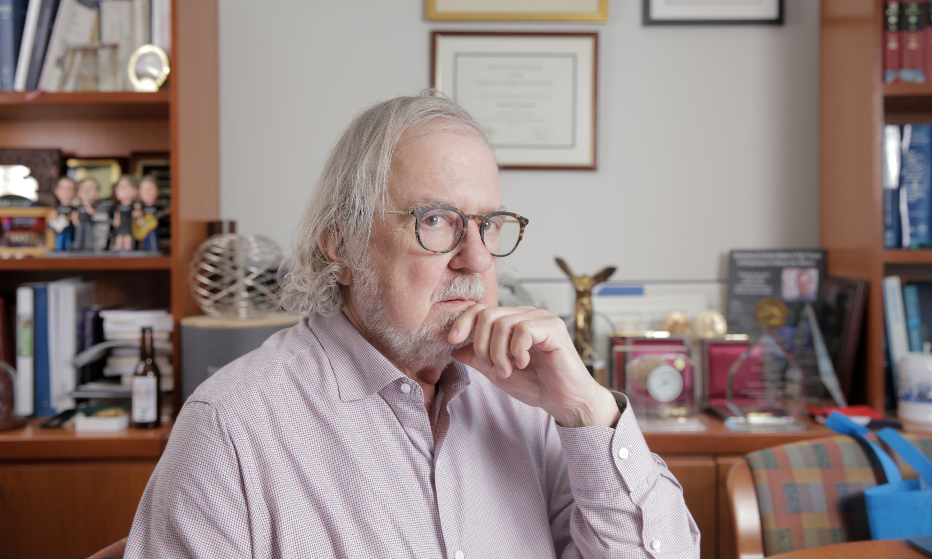 Photo of James P. Allison sitting at his desk at the MD Anderson Cancer Center.