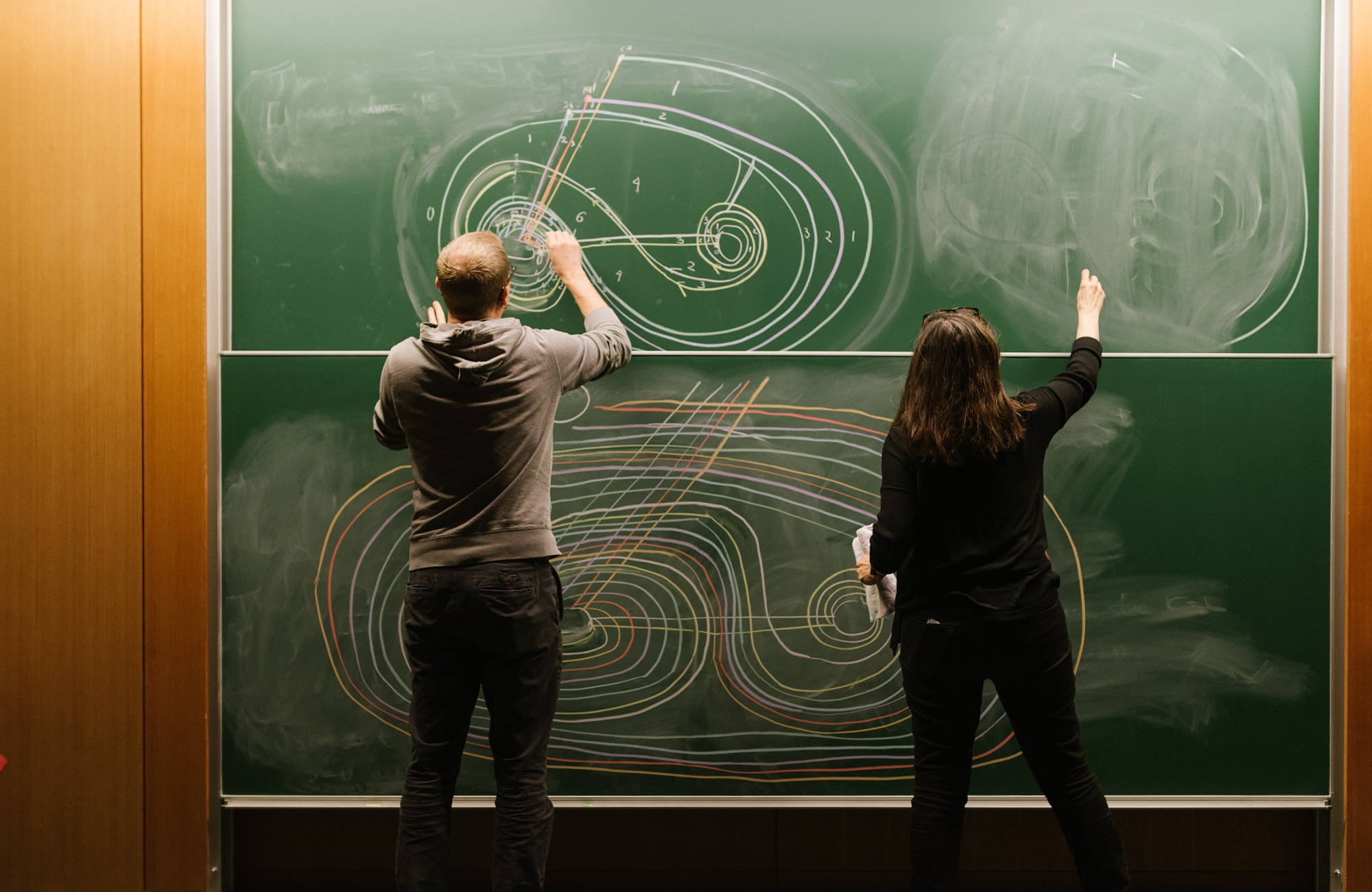 Photo of two mathematicians drawing on a chalkboard