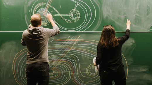 Photo of two mathematicians drawing on a chalkboard