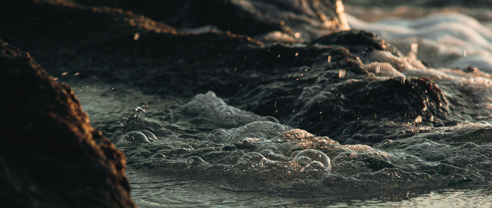 Close-up of water swirling among rocks at the sea’s edge.