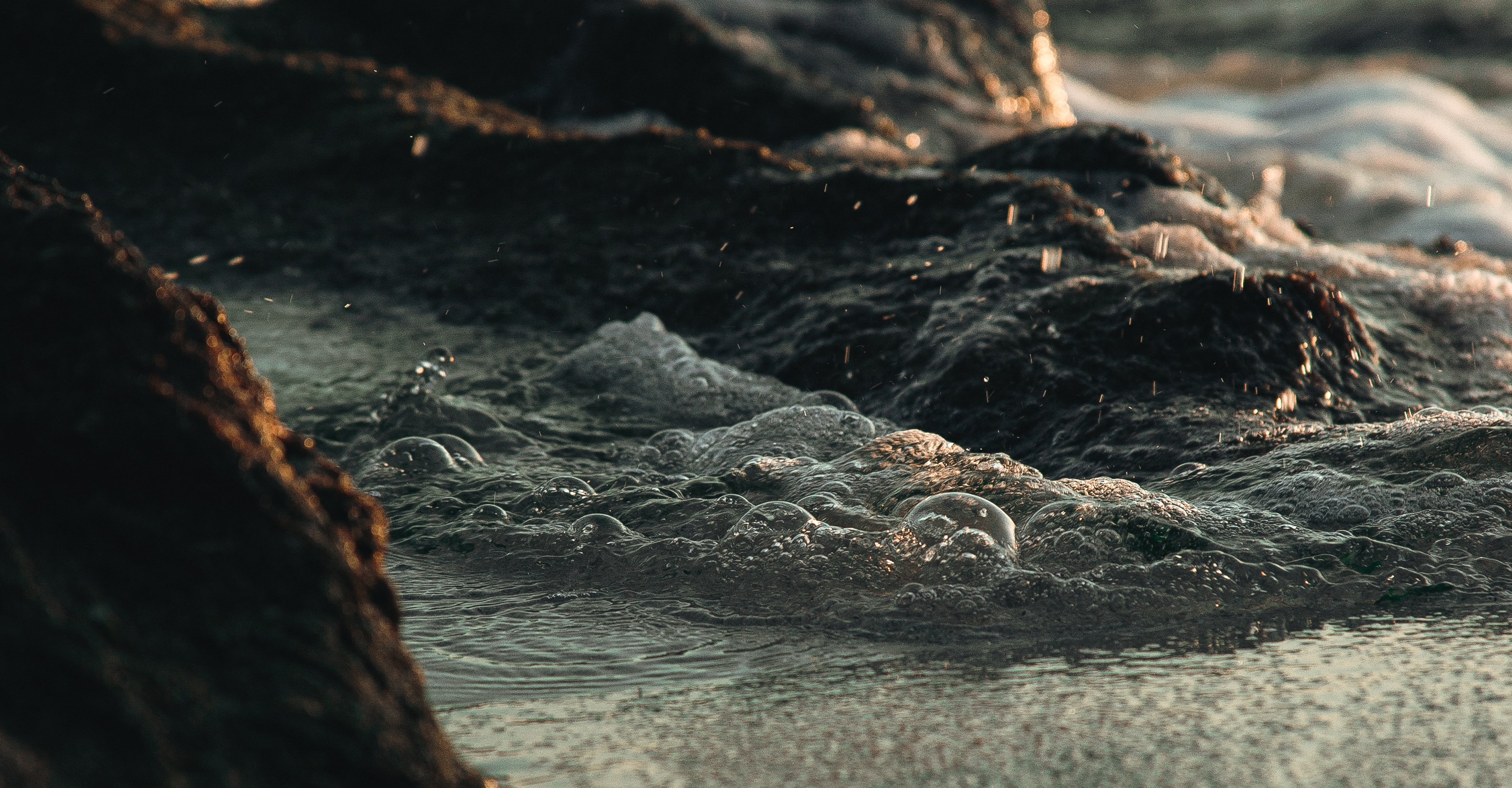 Close-up of water swirling among rocks at the sea’s edge.