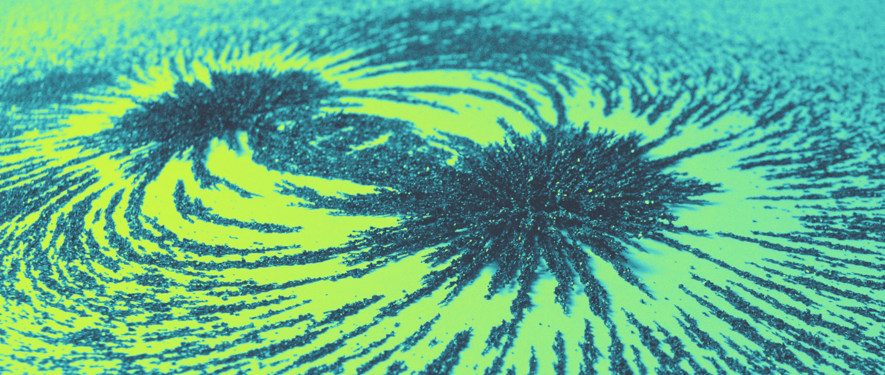 Photo of iron filings spread along magnetic field lines on a green and yellow background