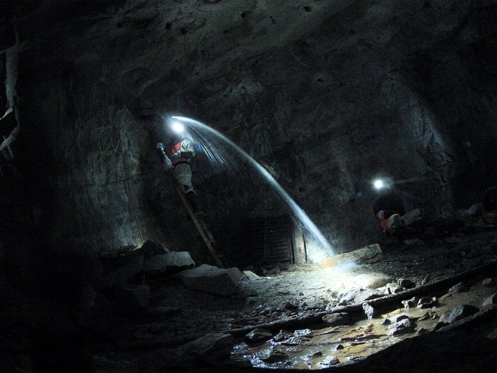 Water gushes through the wall of a mineshaft.