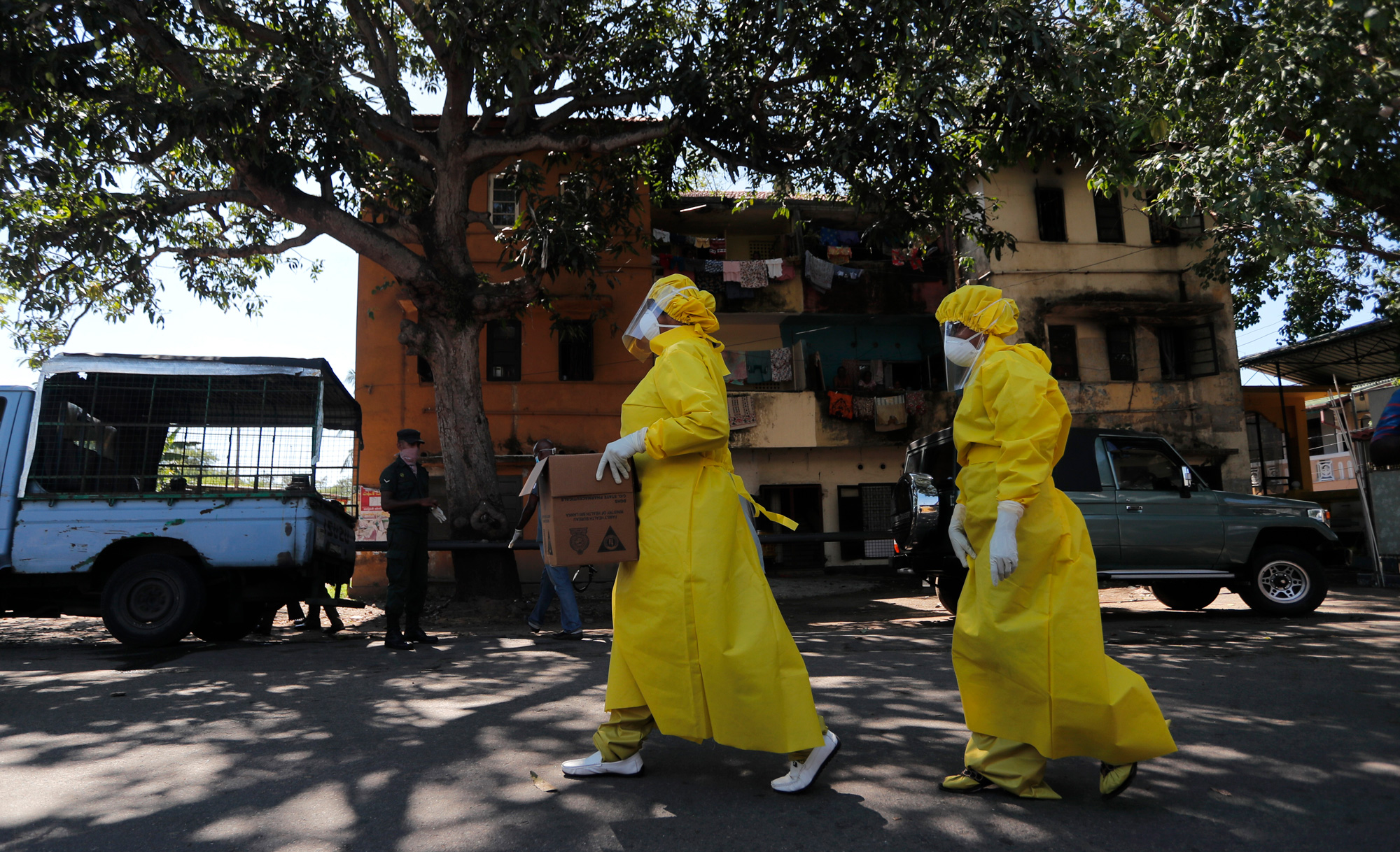 Medical workers garbed in protective gear walk through a neighborhood in Columbo, Sri Lanka.