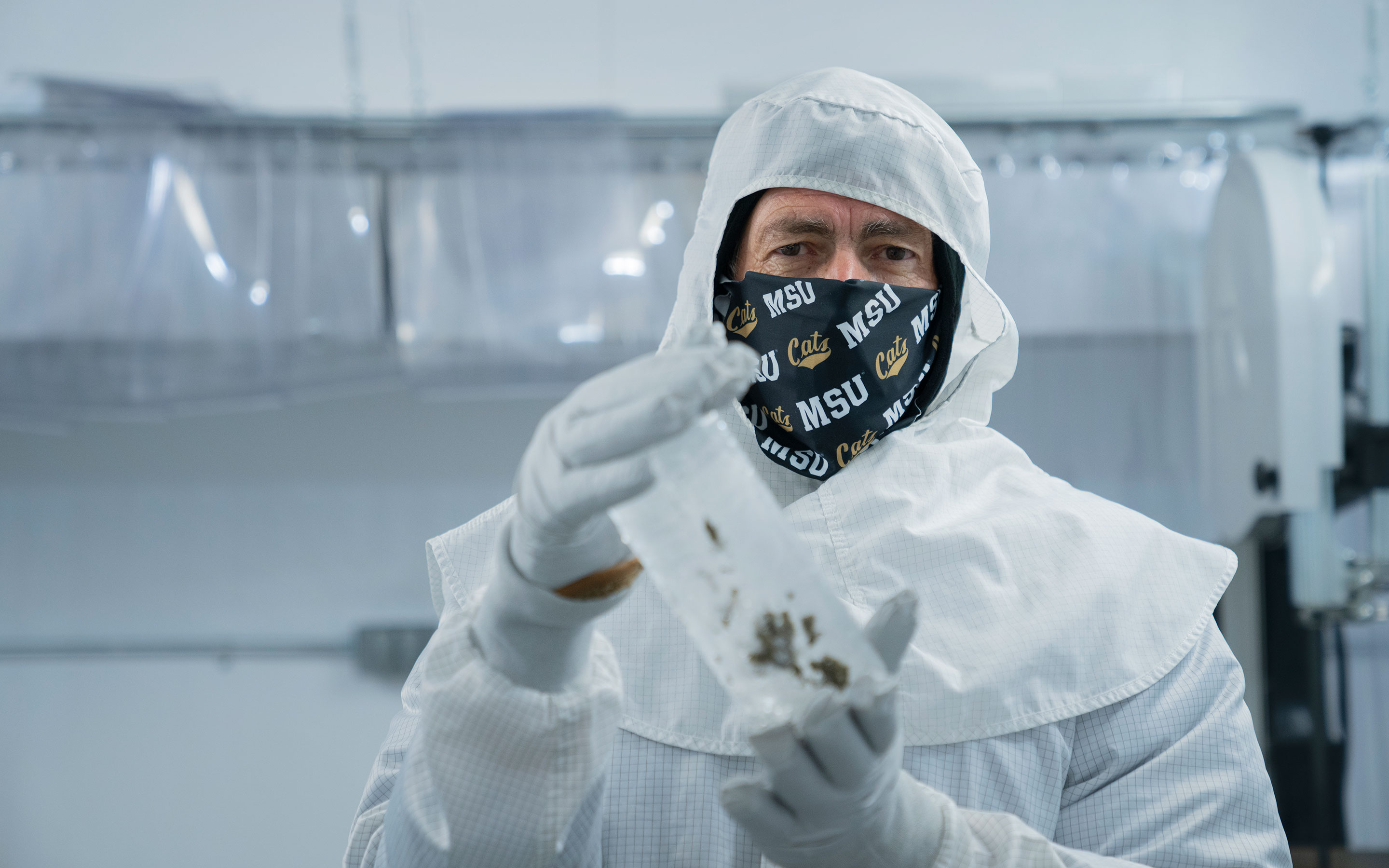 John Priscu holds an ice core sample in a sterile laboratory.