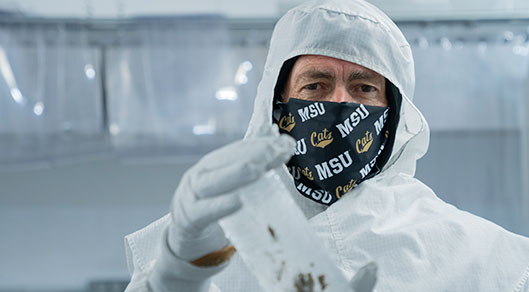 John Priscu holds an ice core sample in a sterile laboratory.