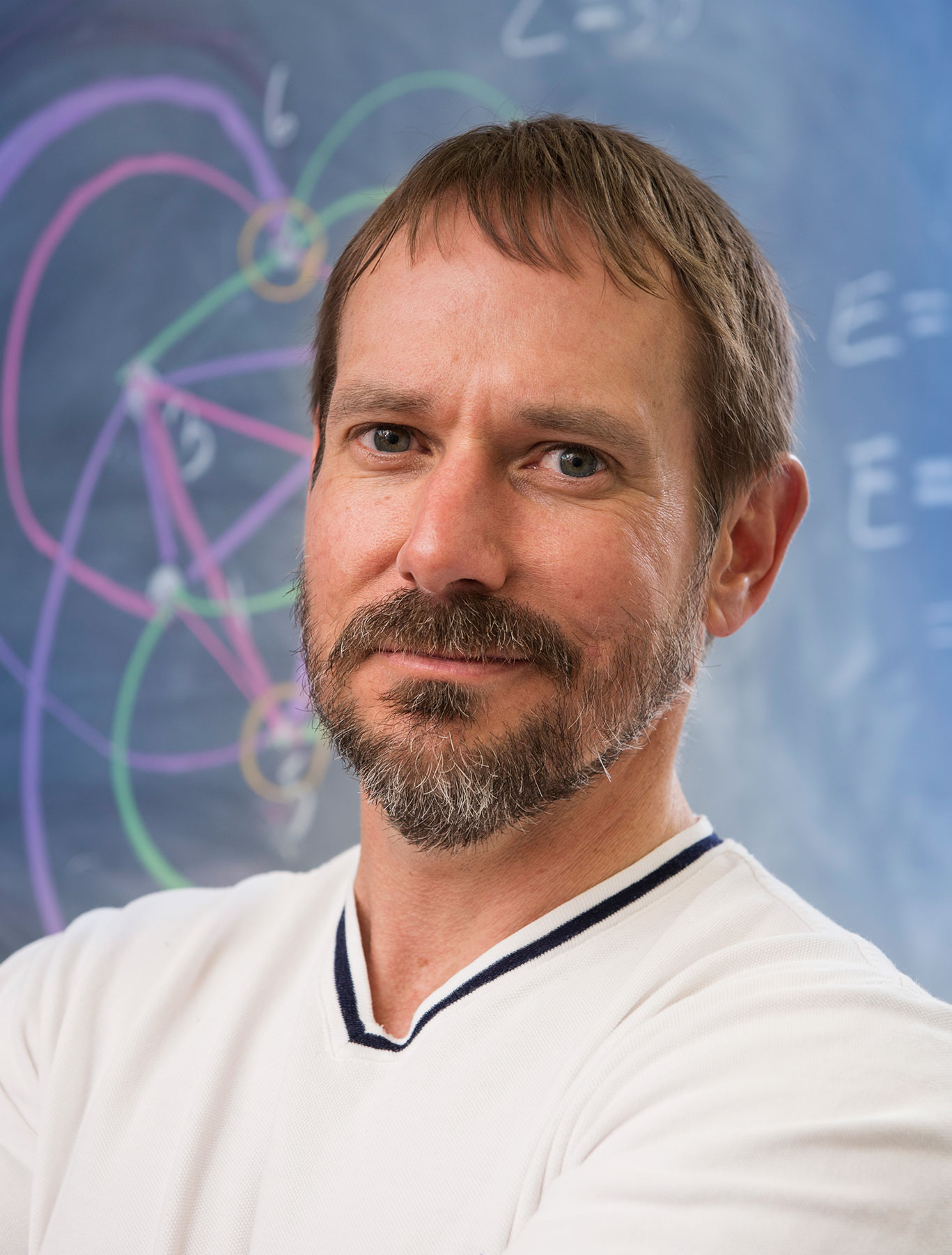 Photo of John Mackey in a white shirt in front of a chalkboard