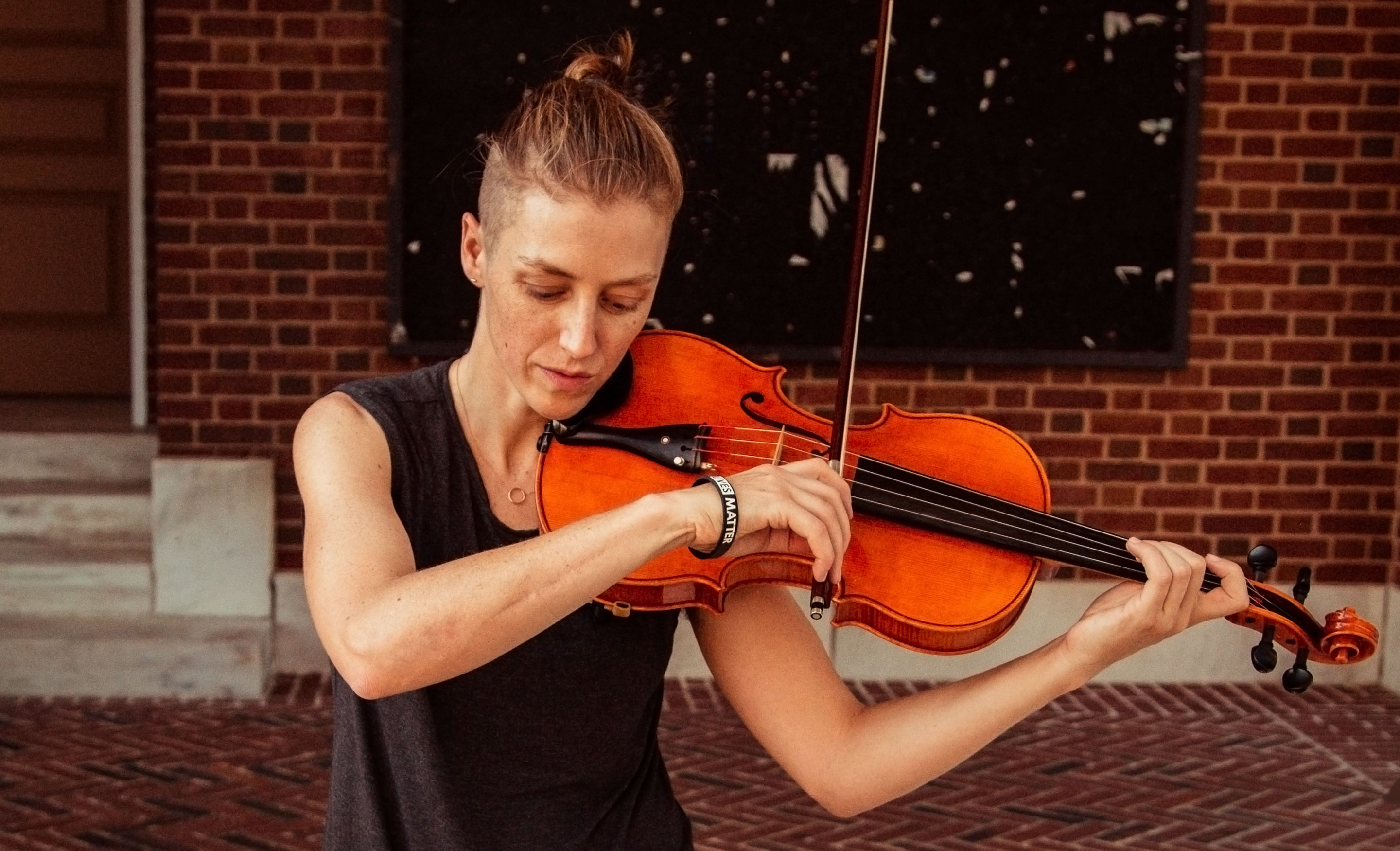 Mathematician Emily Riehl playing the viola outside.