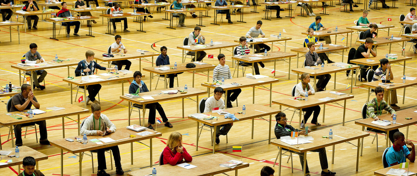 Photo of students sitting at desks competing in the International Mathematical Olympiad