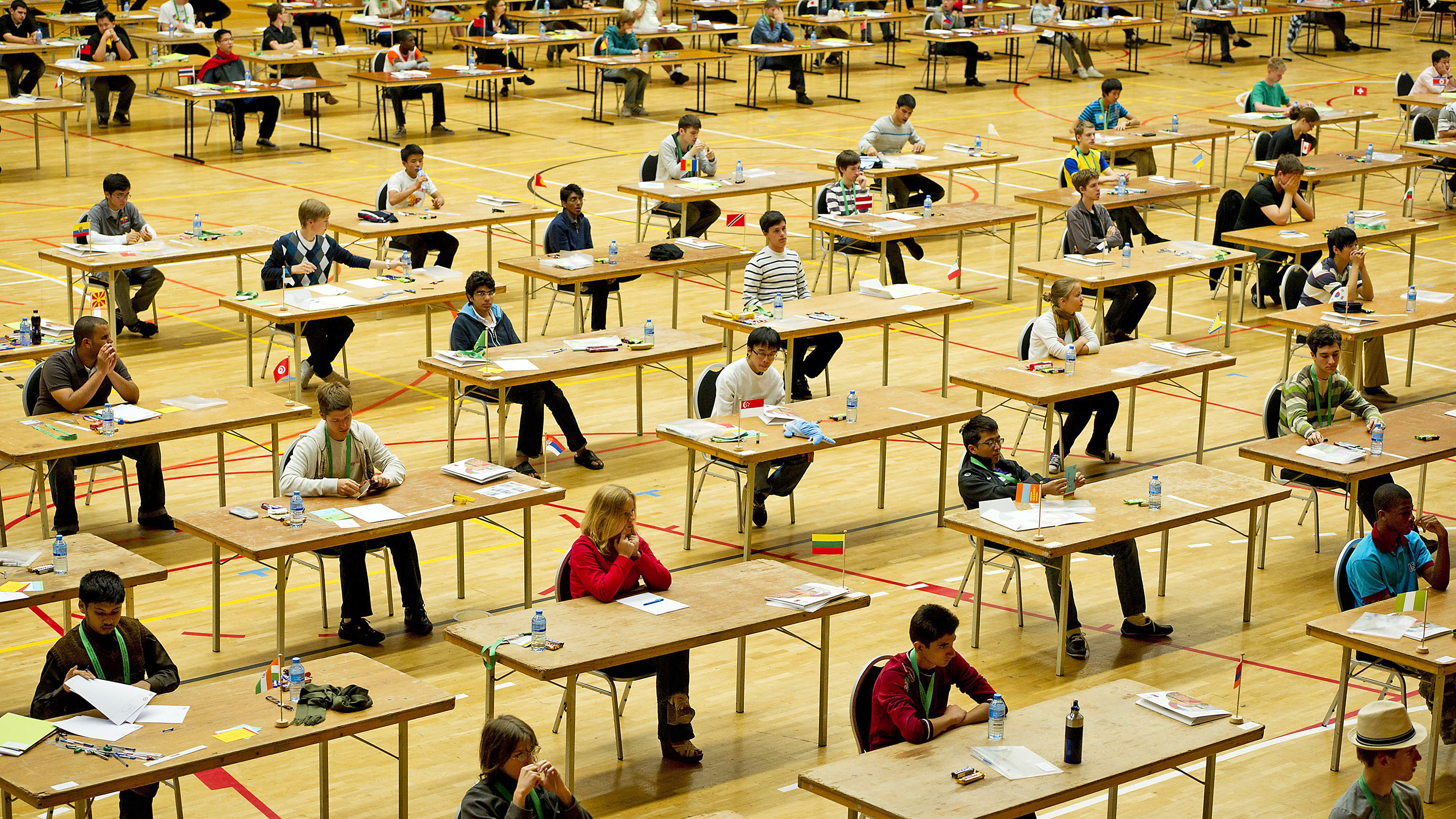 Photo of students sitting at desks competing in the International Mathematical Olympiad