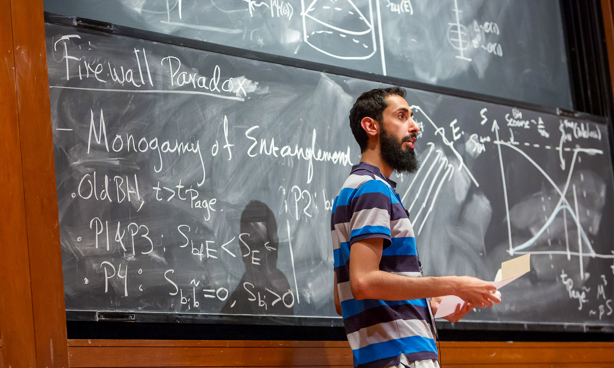 Ahmed Almheiri lecturing about the firewall paradox in front of a blackboard.