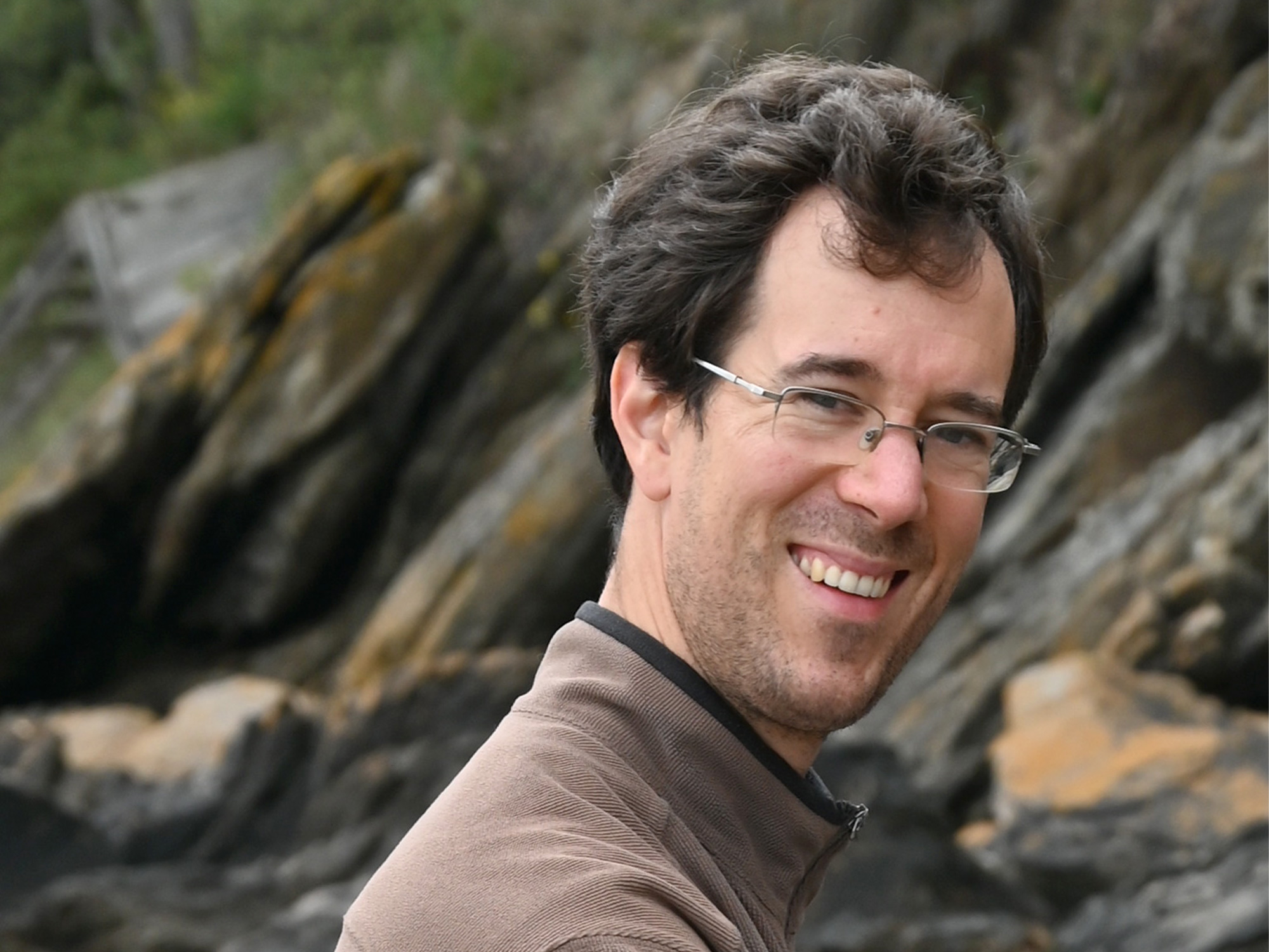 Portrait of Sébastien Gouëzel in front of a rocky area outdoors