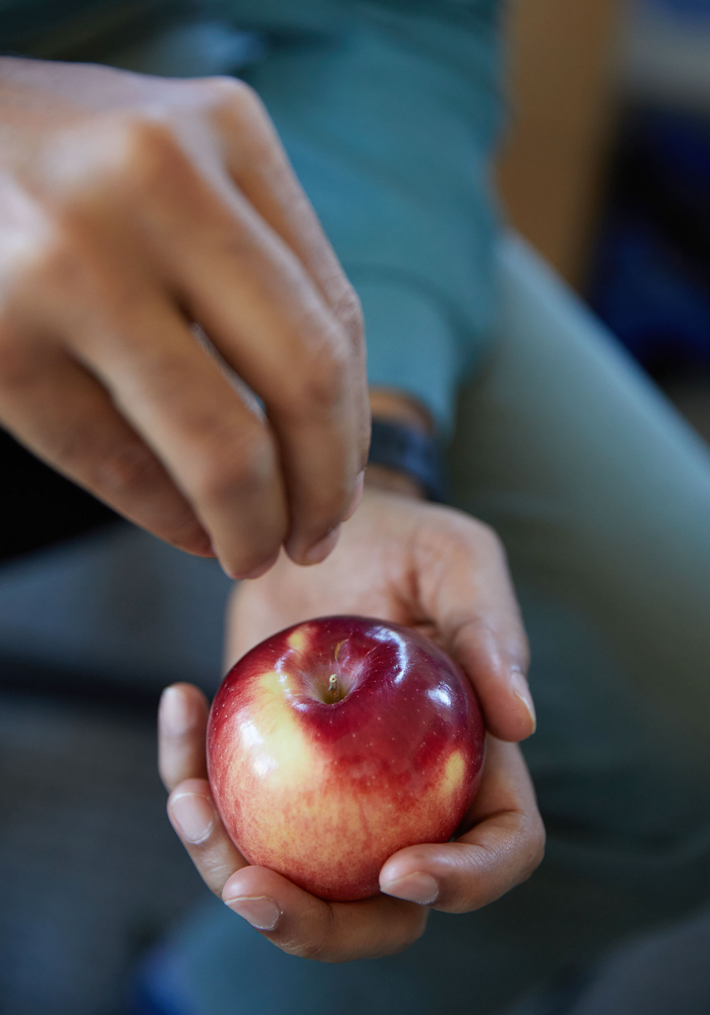 A close up shot of a red apple in Mahadevan’s hand