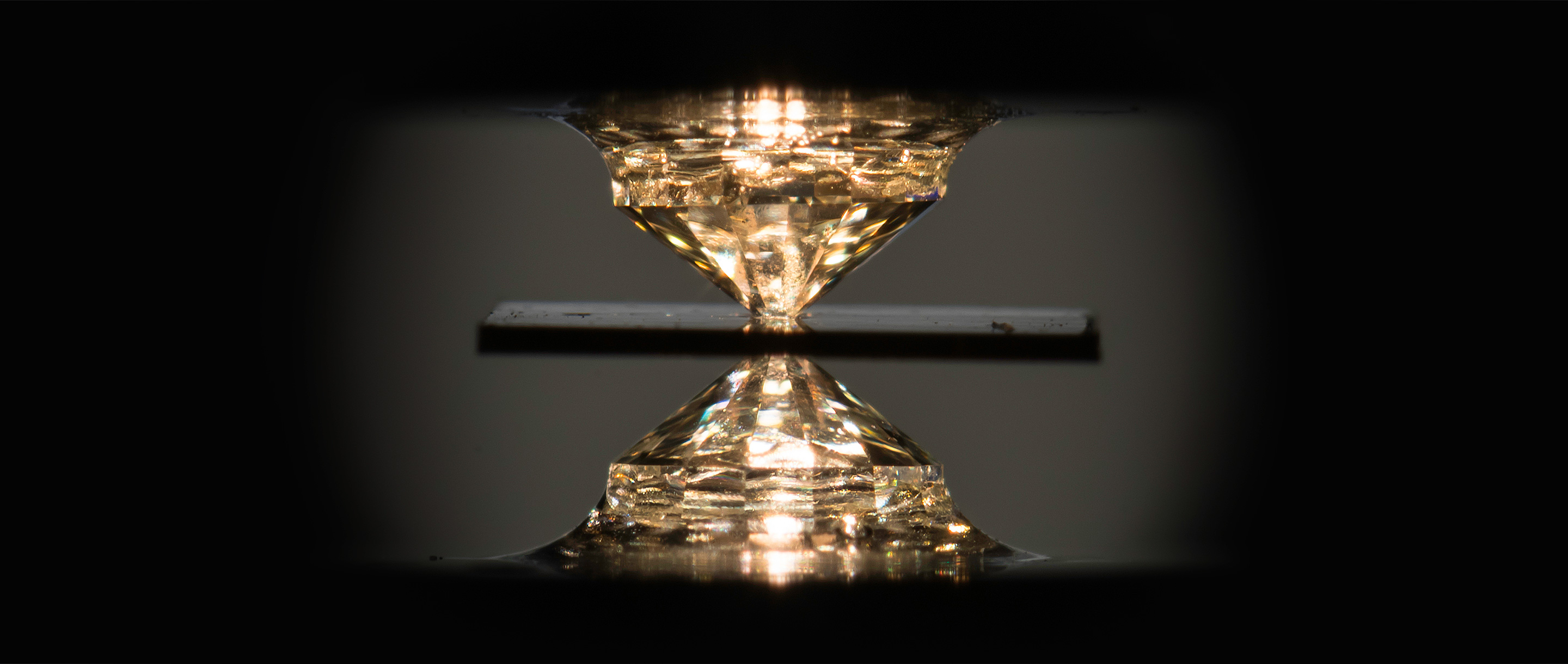 A pair of diamonds press from opposite directions against a black metal gasket containing a hydrogen-carbon-sulfur compound.