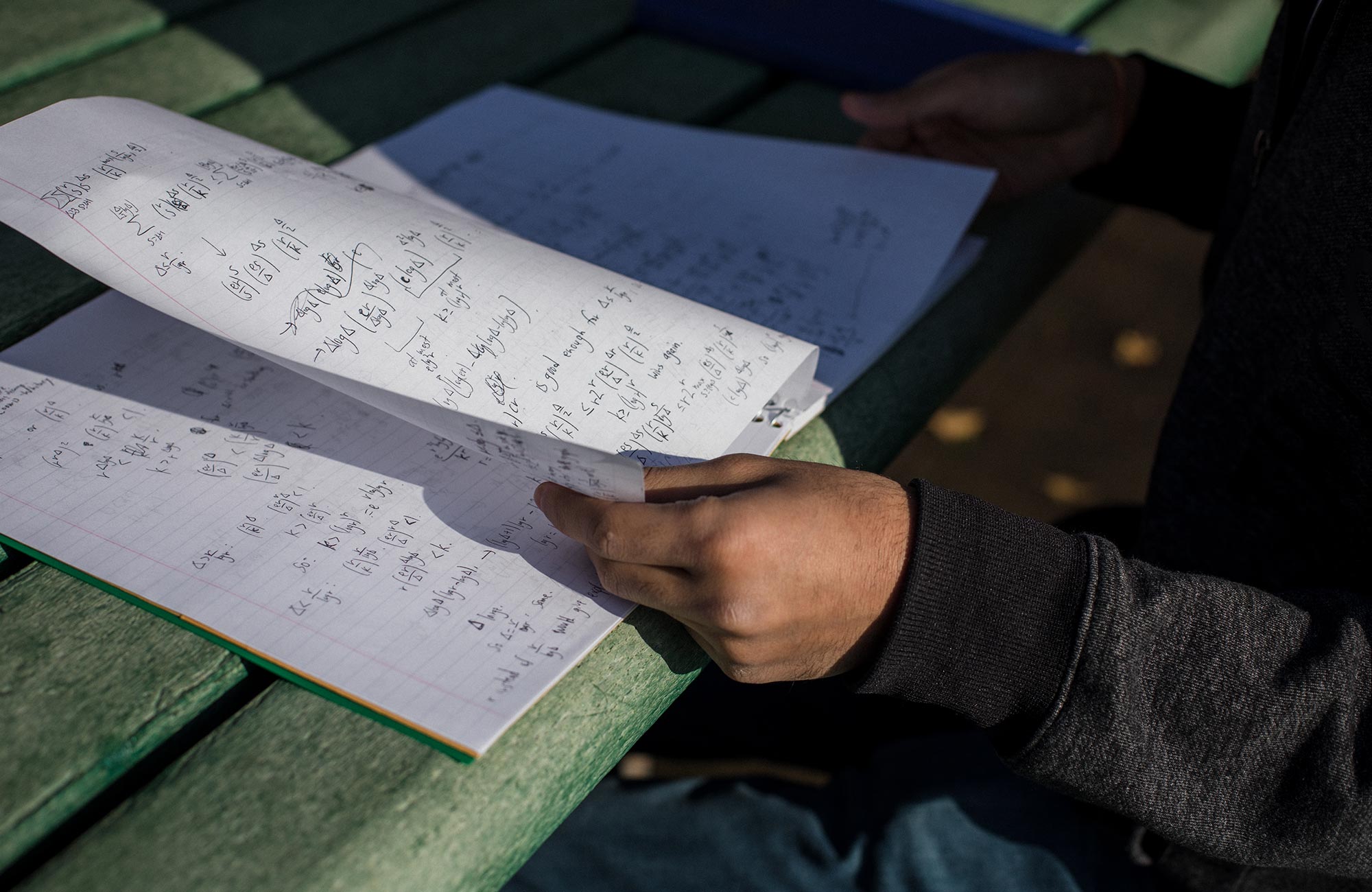 A photo of Ashwin Sah working at a park table, and a photo of his notebook