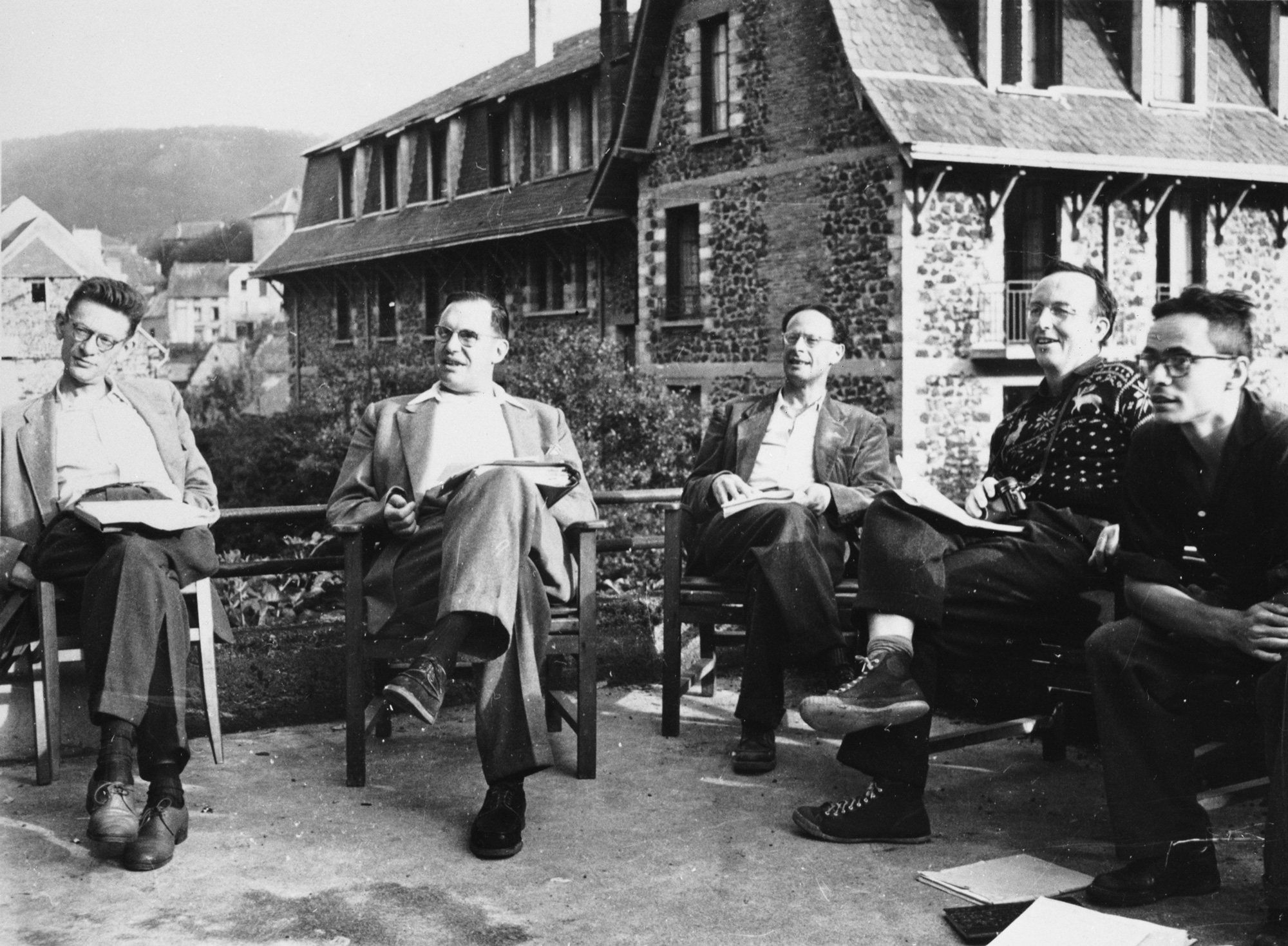 Black and white historical photo of five men sitting on a rooftop