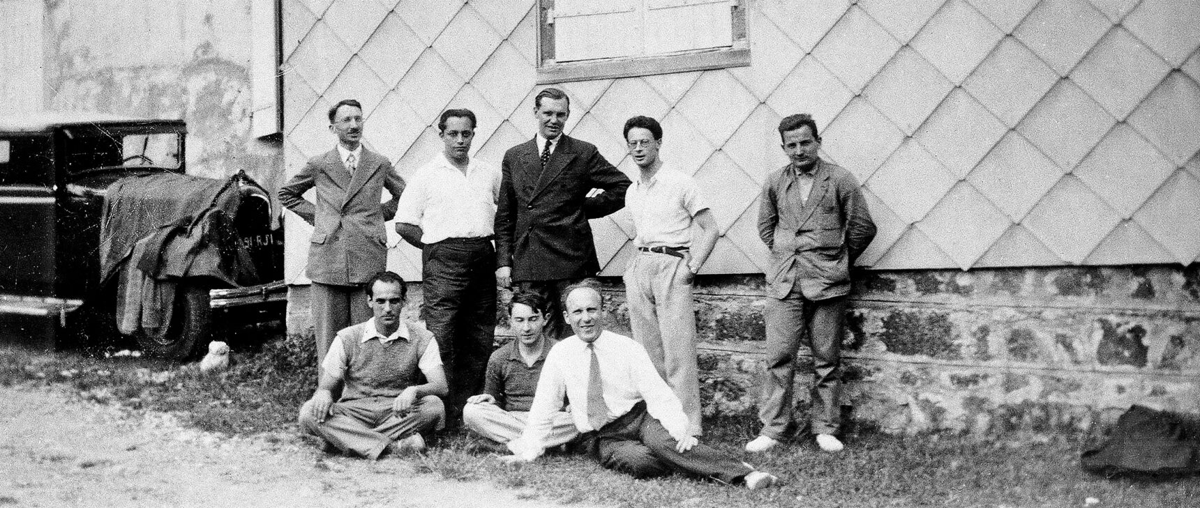 Black and white historical photo of eight men in front of a building, including Henri Cartan, André Weil and Szolem Mandelbrojt.