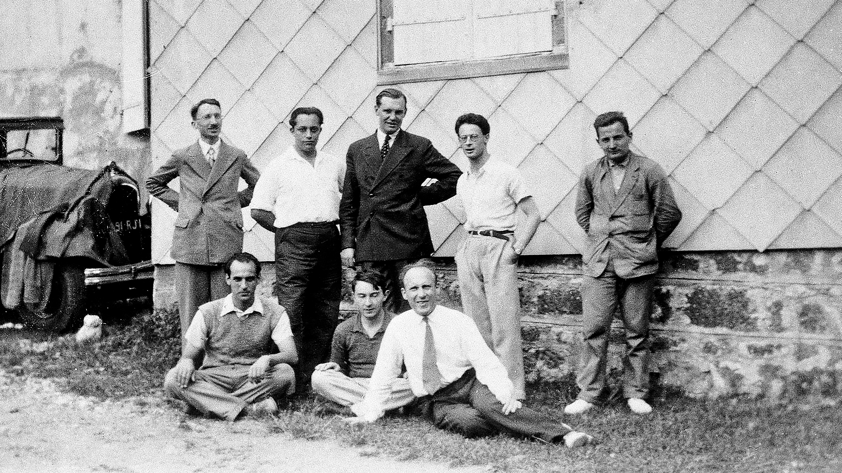 Black and white historical photo of eight men in front of a building, including Henri Cartan, André Weil and Szolem Mandelbrojt.