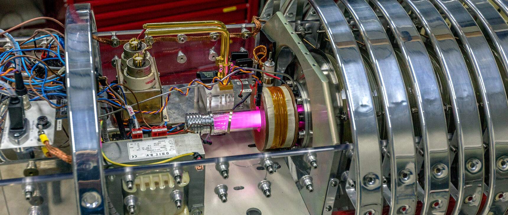 A pink beam at the center of a metallic experimental apparatus.