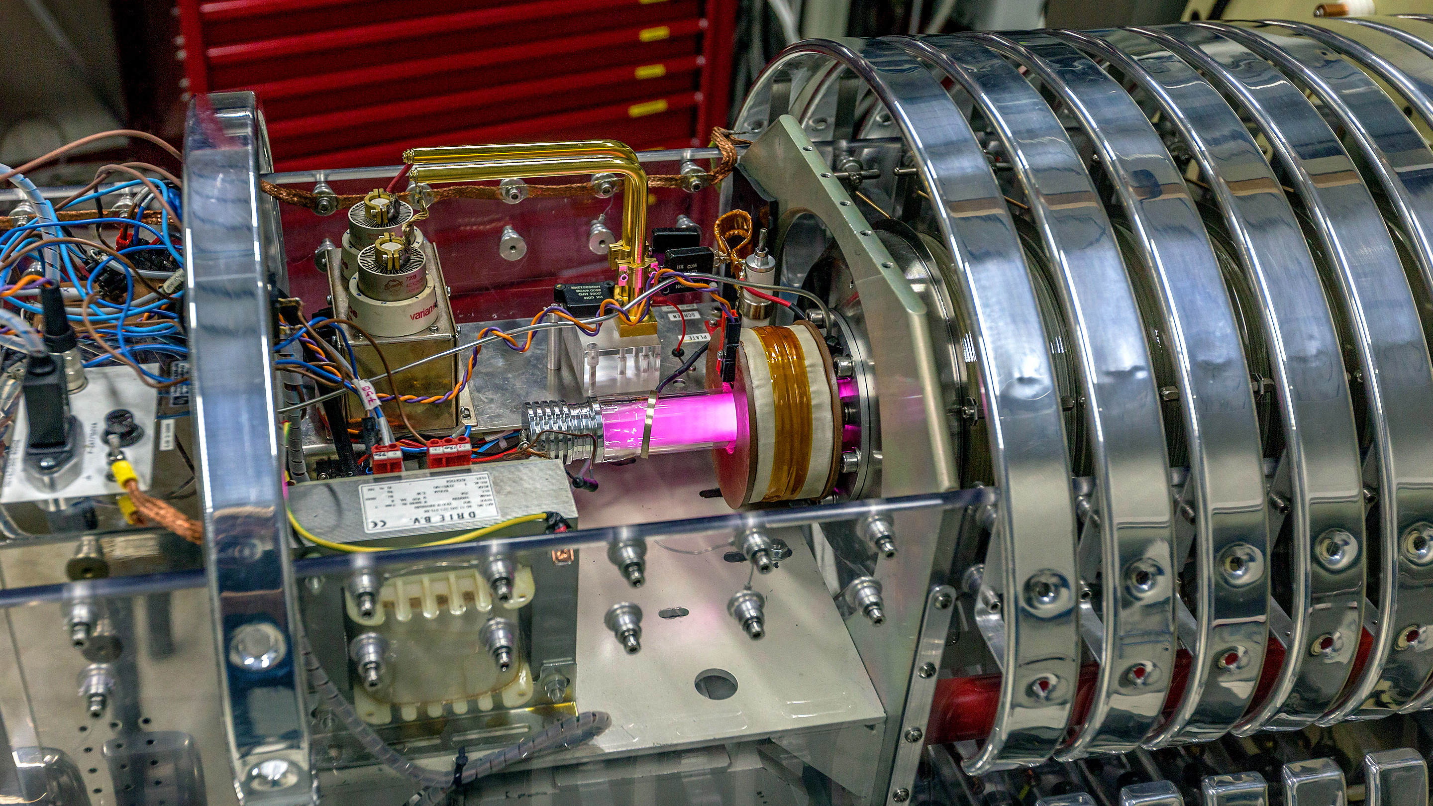 A pink beam at the center of a metallic experimental apparatus.