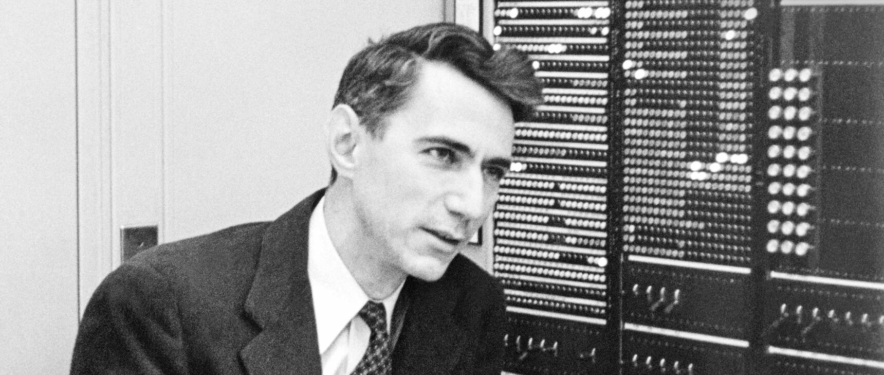 Black and white photo of Claude Shannon in front of a computer