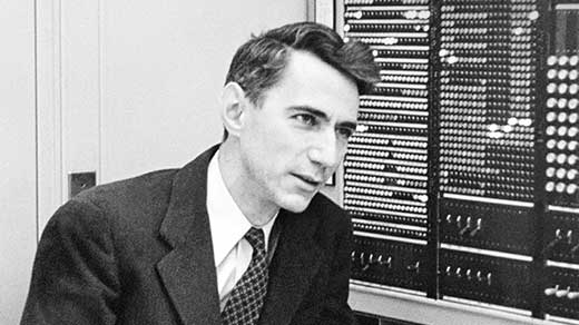 Black and white photo of Claude Shannon in front of a computer