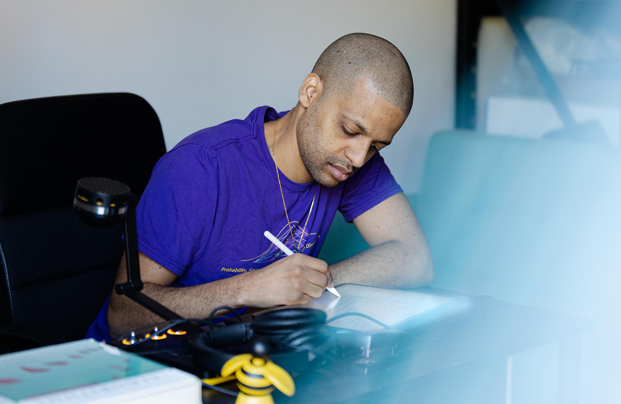 A close-up of Jelani Nelson as he writes at his desk.