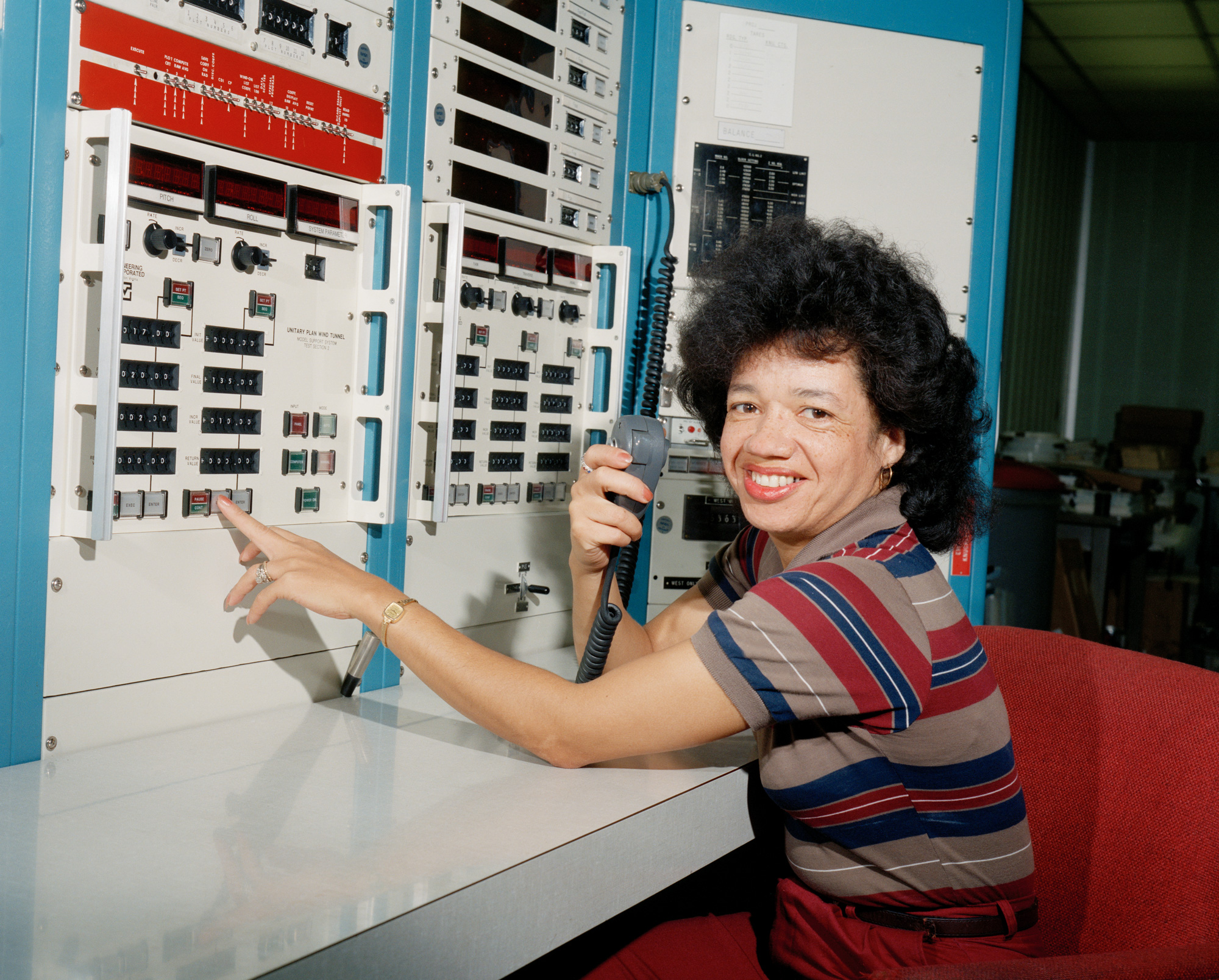 Historical photo of Darden in a striped shirt sitting in front of a large computer console.