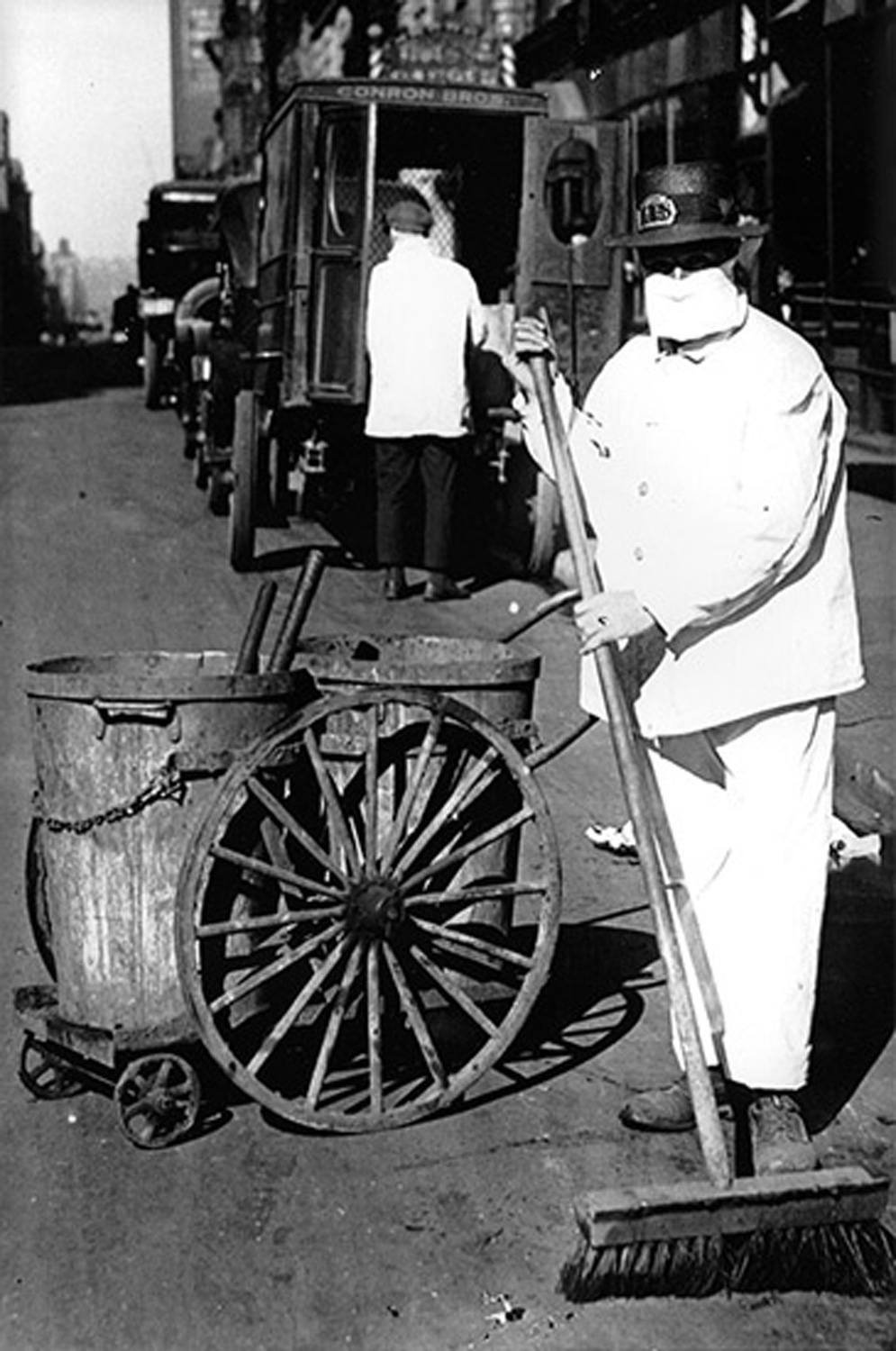 Two photos from the 1918 influenza pandemic: a poster warning people to stay home and a street sweeper in a mask.