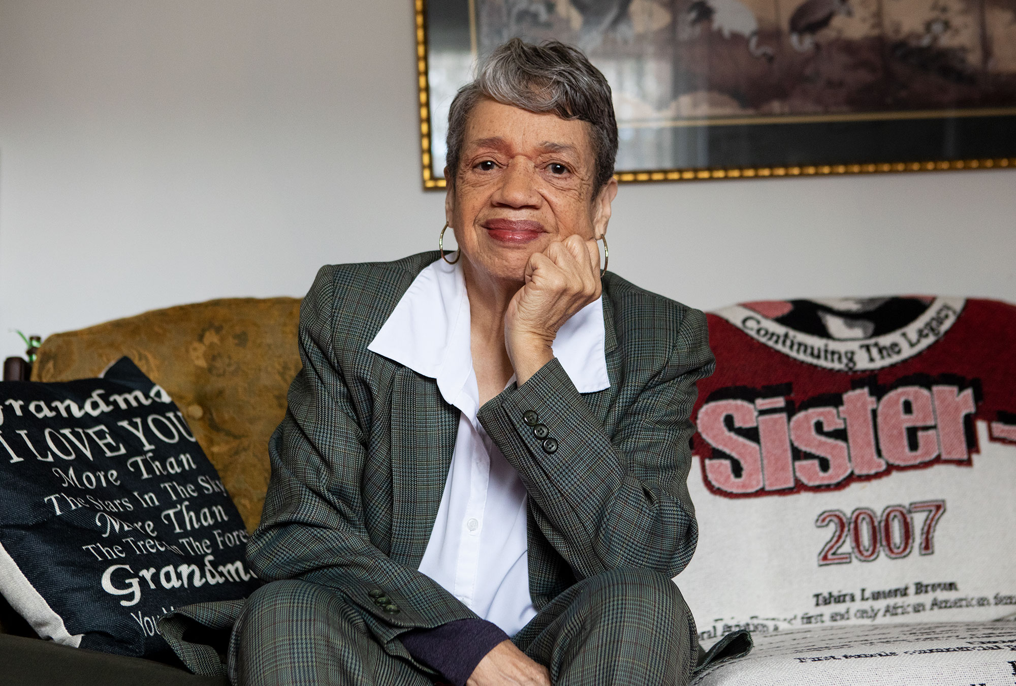 Photo of Darden sitting on her couch and smiling