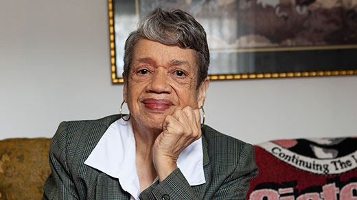 Photo of Darden sitting on her couch and smiling