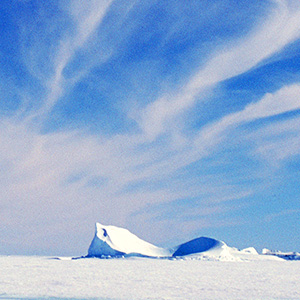 Photograph showing cirrus clouds in a blue sky above an expanse of flat, snow-covered ice.